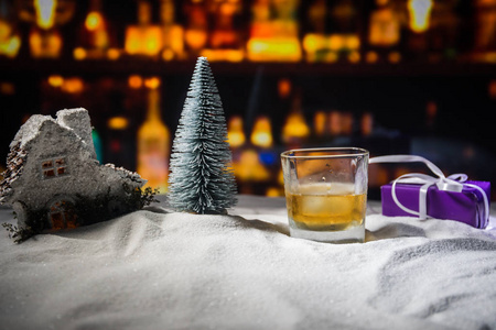 雪上带威士忌的玻璃和艺术品圣诞装饰。 白色雪地上的一杯威士忌，有着美丽的节日背景。 复制空间