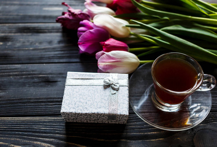 五颜六色的郁金香在灰色的木桌上放着盒子和一杯咖啡。 情人节春天的背景。 花卉模拟。 与共空间