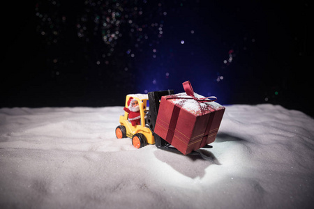 微型礼品盒由叉车在雪地上确定圣诞假期的形象和新年快乐礼物庆祝的概念。 选择性聚焦