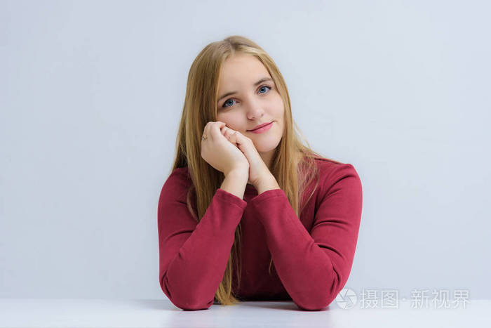 概念肖像一个美丽的快乐金发女孩在白色背景微笑,与情绪交谈,坐在桌子
