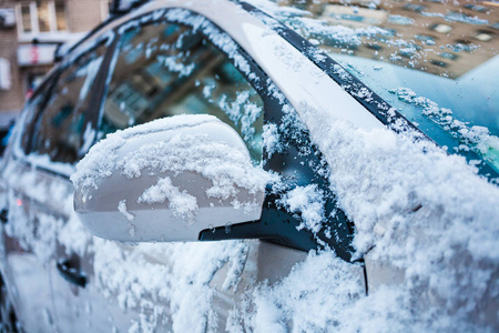 白雪覆盖的汽车。冬季停车。后视镜上覆盖着雪。