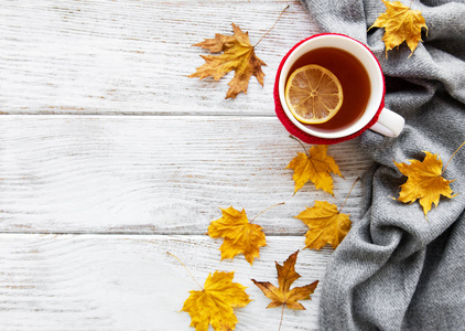 秋天在木制背景上平躺着，杯茶和枯黄的落叶