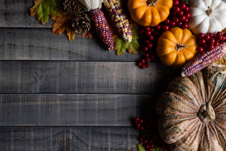 秋天枫叶的顶部视图与南瓜，苹果玉米和红色浆果在旧的木制背景。 感恩节的概念。