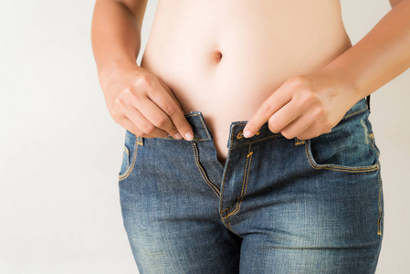 超重的胖女人穿牛仔裤。 减肥胃特写。 紧身牛仔裤在健康苗条的身体上。 饮食观念。