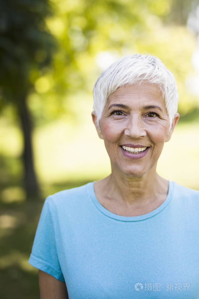 夏日公园里一位笑容可掬的老年妇女的画像