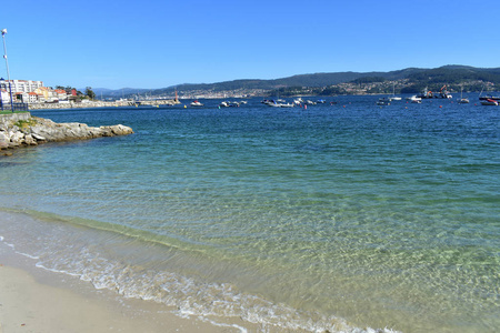 有清澈水域和泡沫的小海滩。 沙子和绿松石水，绿色和蓝色。 晴天的海洋和海岸线。 加利西亚西班牙。