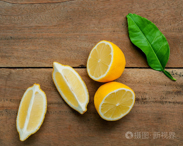 新鲜柠檬和柠檬叶子在乡村木制背景上。 新鲜柠檬和柠檬片在木制桌子上，平躺着。 新鲜柑橘果实背景。