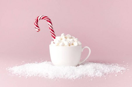 圣诞节新年饮料白色杯子与棉花糖和糖果在雪地上粉红色背景平躺复制空间。 冬季传统饮料食品。 节日装饰庆典2019年圣诞节