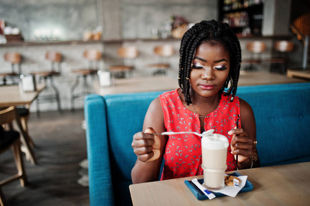 漂亮的非裔美国女人坐在桌上拿铁咖啡。