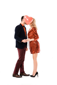 有魅力的一对夫妇牵手接吻，同时把脸藏在白色气球上的红色气球后面