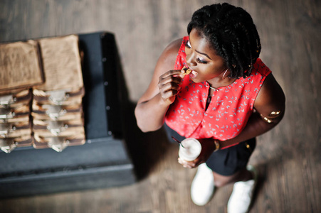迷人的非裔美国女孩摆姿势在咖啡馆拿铁和饼干在手边。 从上面看。