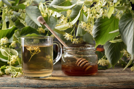 木桌上放着蜂蜜和花的林登茶。