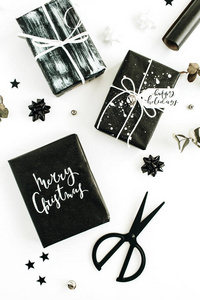 白色背景上的黑色自制礼品盒和装饰品。 圣诞快乐，节日快乐。 平躺顶景节日构图。