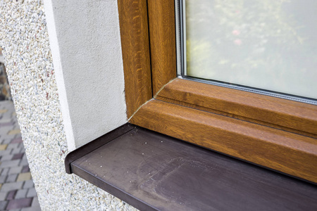 关闭屋用新安装的棕色塑料窗和金属窗台关闭白色抹灰屋墙的细节.