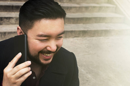 亚洲商人与手机快乐的谈话在商业背景。生活方式