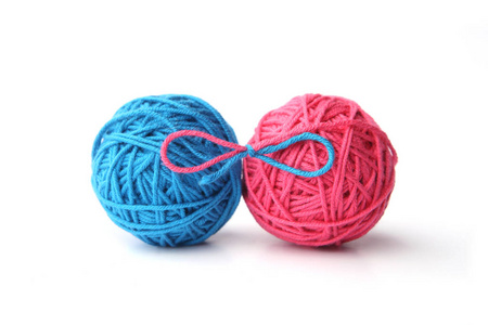 两个粉红色和蓝色棉线球系在蝴蝶结上，孤立在白色背景上。 不同颜色的粉红色和蓝色线球。
