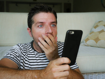 的男人用手机看网络社交媒体或查看新闻,惊讶和疯狂,不敢置信的表情