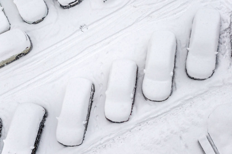 停车场里有雪覆盖的车。 城市场景。 暴风雪过后。 从雪地上清洁汽车