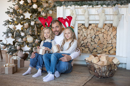 爸爸和两个女儿坐在圣诞树附近