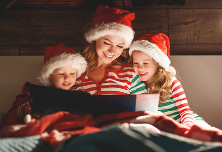圣诞快乐 家庭母亲在睡觉前给孩子们读一本书