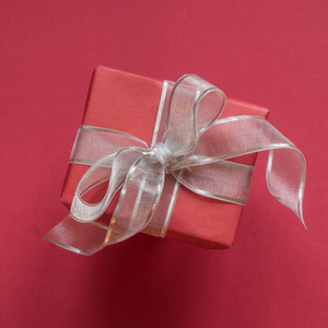 礼品盒在红纸上，红色表面有银丝带。 上面的风景。