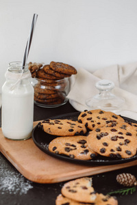 带鲜牛奶的玻璃和自制巧克力饼干在黑暗的桌子上。