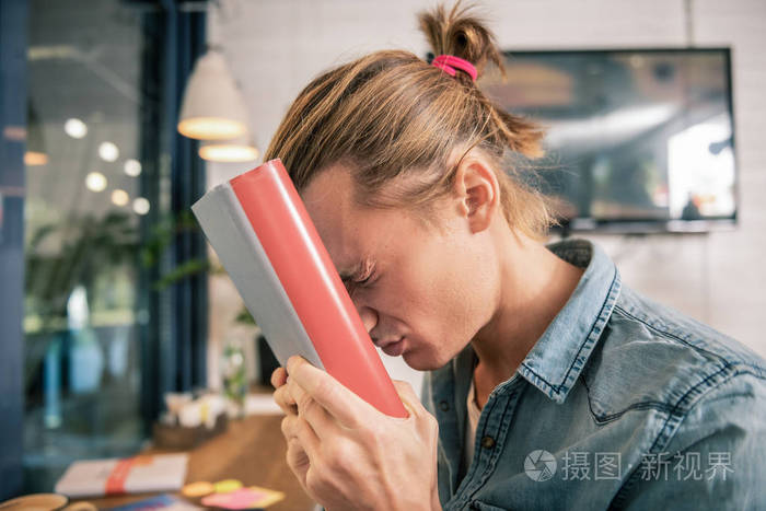 沮丧的不愉快的人拿着一本厚厚的书