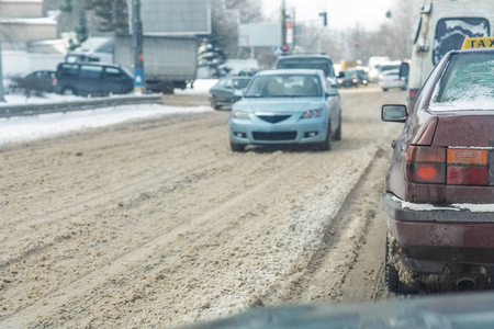 冬天，汽车在雪滑的道路上行驶在城市街道上。 在寒冷的冬季降雪和暴风雪后，覆盖着雪漂移的车辆。 天气预报。