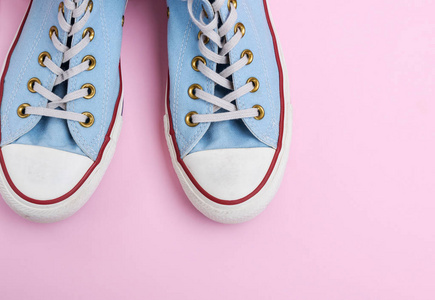一双破旧的蓝色运动鞋，上面有粉红色背景的白色鞋带