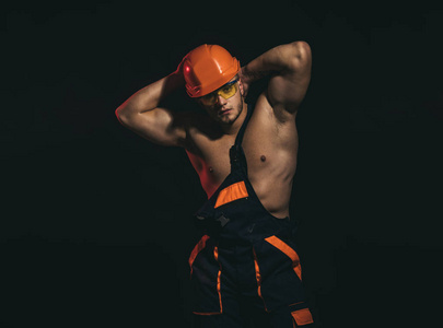 我的工作一定会给人留下深刻的印象。建筑工人或建筑工人。男子工人与肌肉的身体。英俊的工人或工人。肌肉发达的人戴着硬帽子和制服。