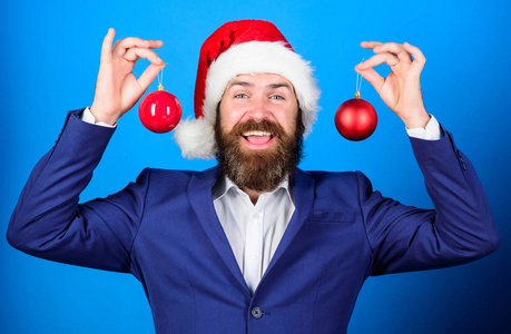 男人留胡子穿正式西装和圣诞老人的帽子。商人参加圣诞节的庆祝活动。圣诞老人举行圣诞舞会装饰。圣诞快乐。圣诞气氛四起。娱乐的目的是