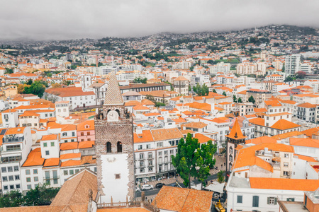 多云天气下，马德拉岛首府Funchal古镇的鸟瞰图。 大西洋边有橙色屋顶的小房子。
