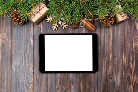 数字平板电脑模拟与乡村圣诞木背景装饰的应用程序演示。 顶部视图与复制空间。