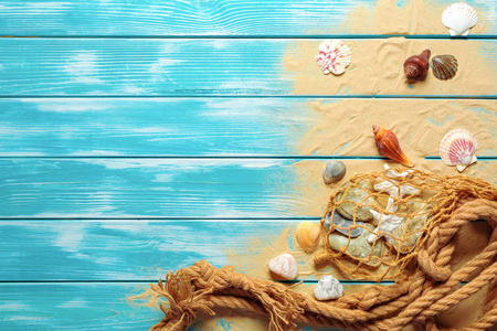 蓝色木制背景上的贝壳和沙子