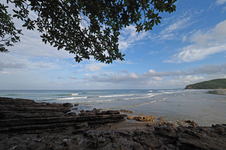 在一个阳光明媚的夏天，尼加拉瓜的Play aelCoco展示了它的海滩岩石植被和云景。