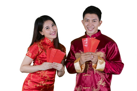 一对年轻的中国夫妇穿着旗袍，在工作室里拿着信封，在白色的背景上被隔离开来