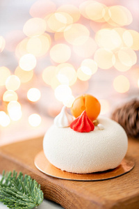 迷你慕斯糕点甜点覆盖着白色天鹅绒花环灯 bokeh 背景。现代欧洲蛋糕。法国菜。圣诞节主题