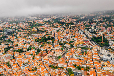 多云天气下，马德拉岛首府Funchal古镇的鸟瞰图。 大西洋边有橙色屋顶的小房子。