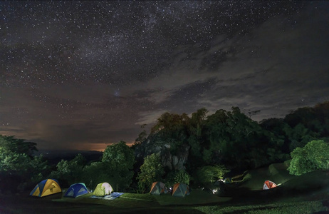 银河系和许多星星在山上，在泰国北部的山峰与露营地点。 天空充满了星星。 星夜与美妙的景观在夏季的概念空间背景和旅游。