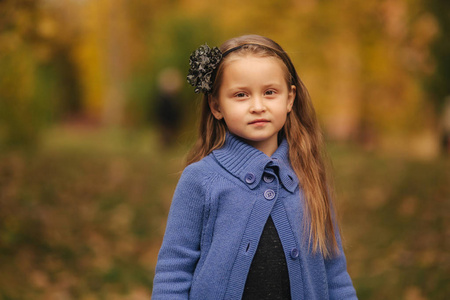 秋天公园里小女孩的肖像。女孩模特向摄影师摆姿势。愉快的孩子