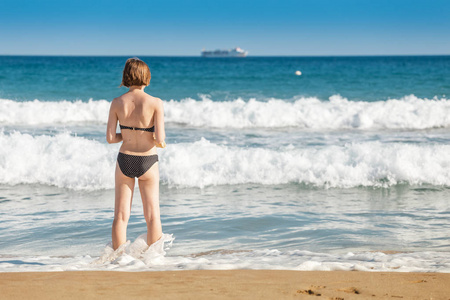 穿着泳衣的年轻女性游客在地中海的波浪状水域享受乐趣，海上风暴天气的概念