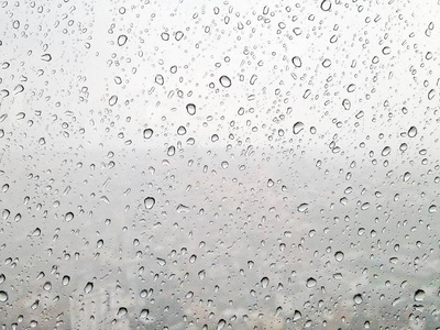 窗玻璃表面的雨滴，在模糊的背景下看到的大雨