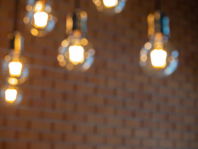 模糊的老式灯泡装饰在咖啡店砖墙背景暖光。