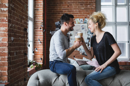 积极微笑的年轻夫妇在家喝咖啡。