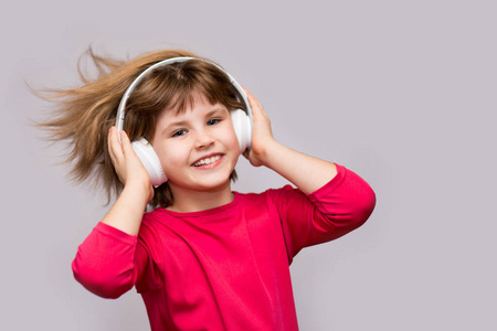 儿童和技术概念微笑女孩带耳机听音乐孤立在白色上。 长发从移动中飞舞。