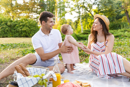 快乐的年轻家庭和小女孩一起在公园野餐