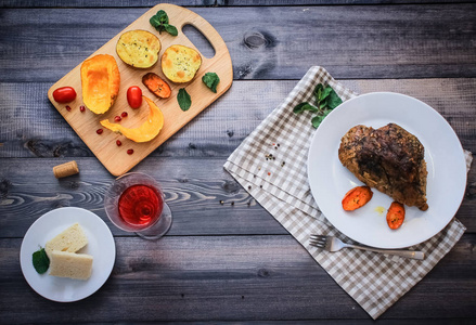一块肉，撒上香料，用烤胡萝卜片烤在白色盘子里，叉子，亚麻布，格子餐巾，旁边是烤南瓜，土豆，香料和樱桃番茄。