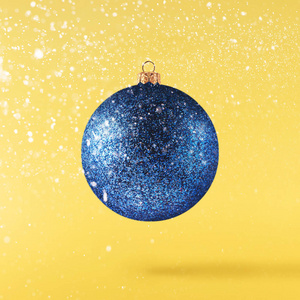 圣诞概念。 创造性的圣诞节概念，由下降在空气中闪闪发光的宝布尔在黄色的背景。 最小概念