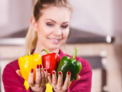 女人手拿着铃铛椒，美味健康的节食蔬菜，呈现三种颜色的饮食食物。