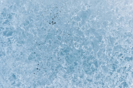 冰川碎片表面的特写镜头, 其结构是条状和气泡, 夹杂着沙子和岩石。冰蓝色的纹理的光。小剂量